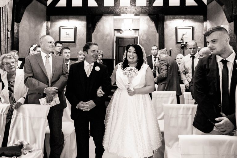 Bride smiles at groom as she walks up the aisle