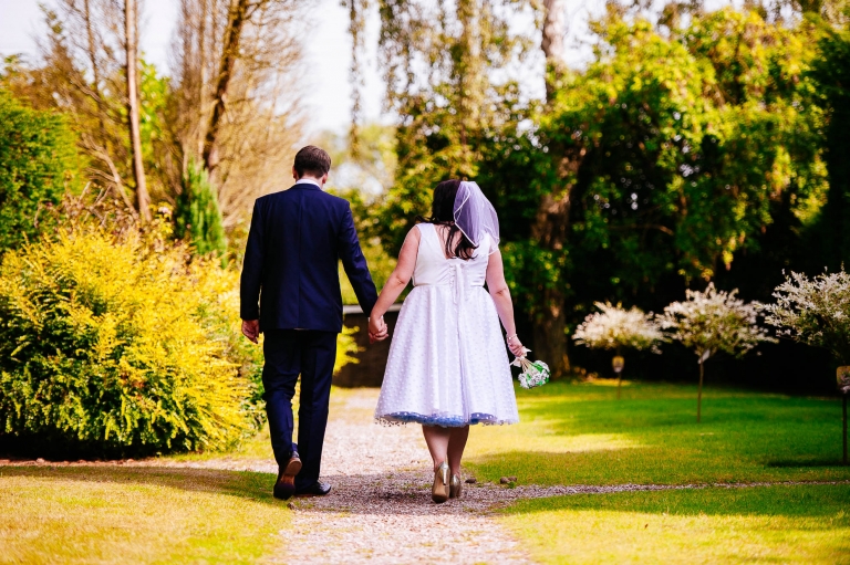 Bride and groom walk through gardens