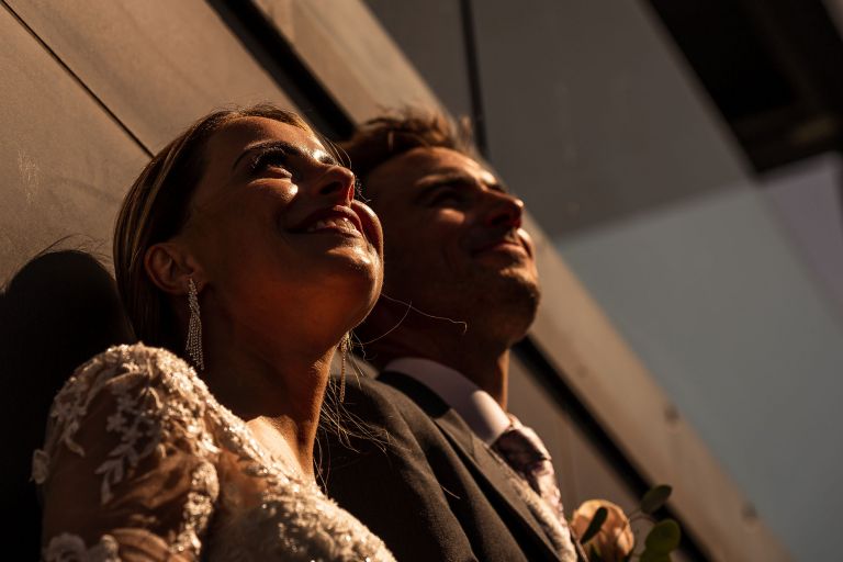 Bride and groom stare into the sun