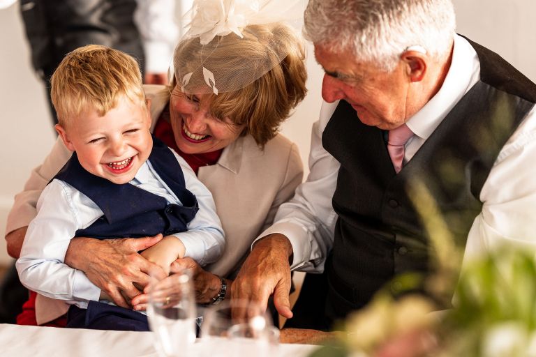 Page boy cuddling and joking with his grandparents