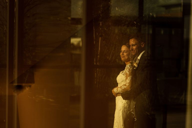 Bride and groom portrait through reflection in window