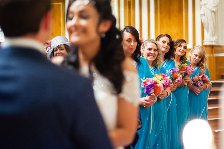 Bridesmaids smiling as they watch the exchange of rings