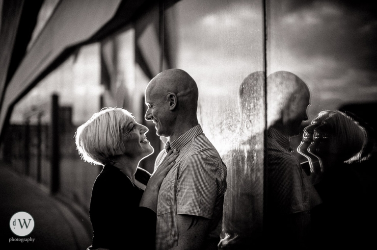 Couple holding each other with reflection in galss