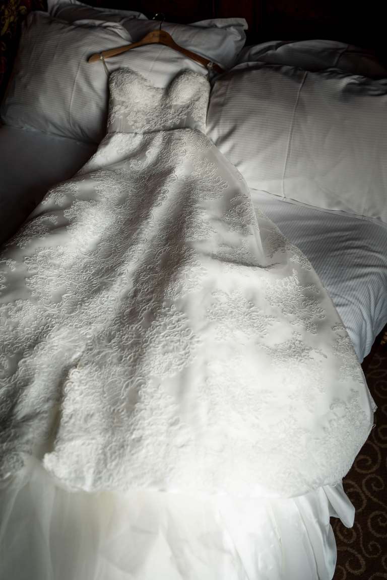 Brides wedding dress on bed