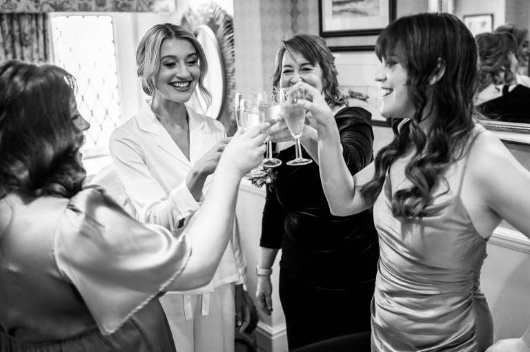 Bride has a glass of prosecco with her bridesmaids