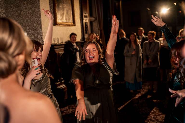 Bridesmaids hands in the air on the dancefloor.