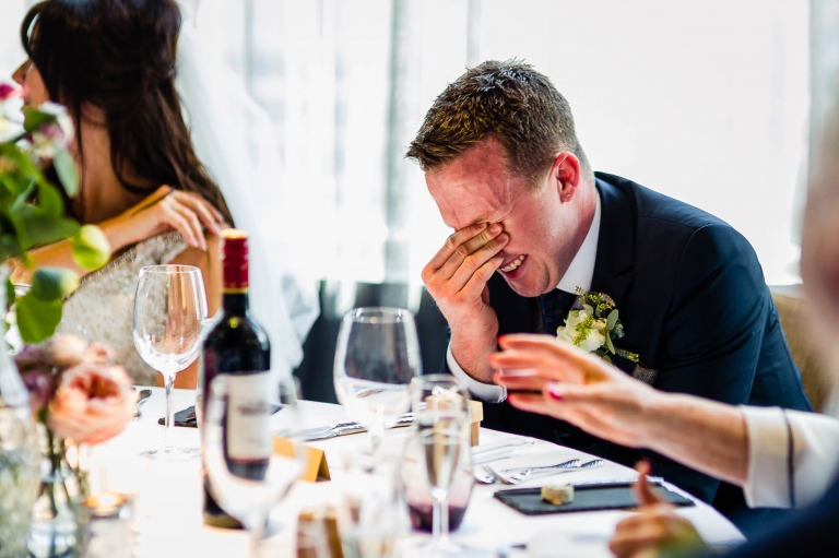 groom's embarrassed laugh as the best man makes fun of him