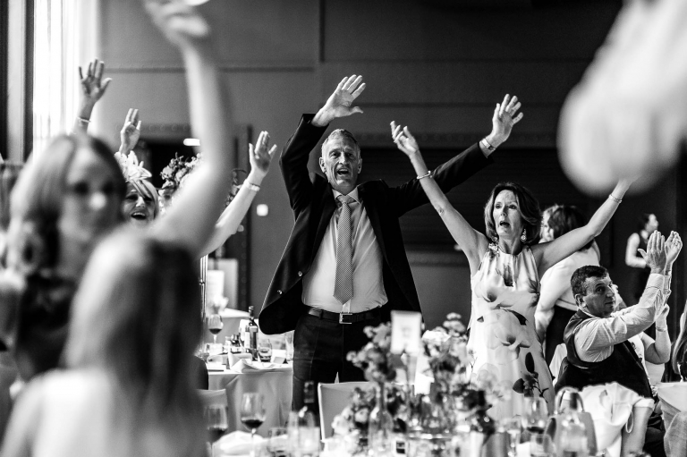 guests wave their hand in the air as the singing waiters perform