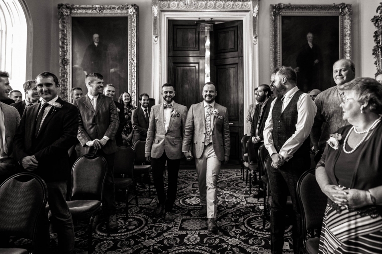 Luke and mike walk down the aisle of the wedding ceremony room in Liverpool Town Hall.