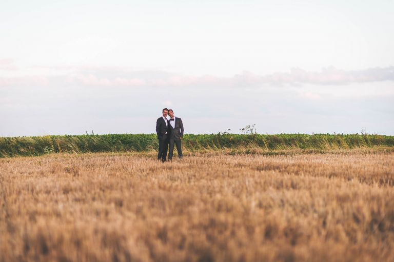 The newlyweds hold each other in a field