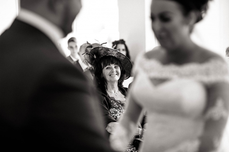 brides aunt looks on and smiles during the wedding ceremony