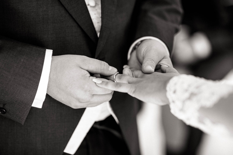 groom places the ring on brides finger