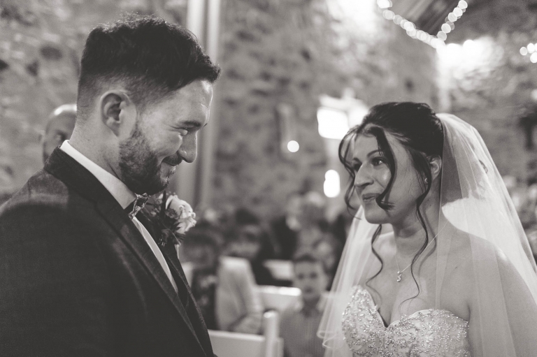 bride and groom smile at each other during wedding vows