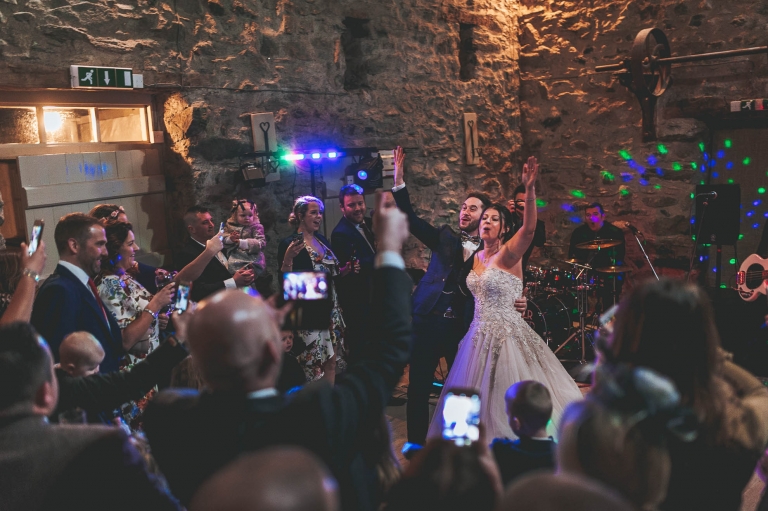 Bride and groom wave hands during first dance