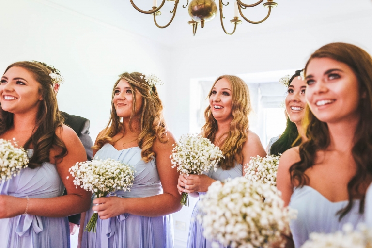 Bridesmaids smile as they see the bride in her dress