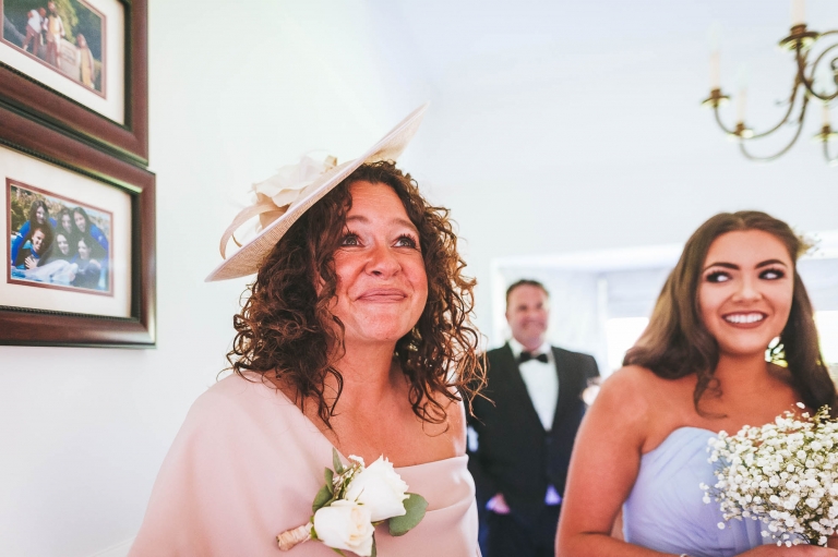 Mother of the bride smiles as she sees her daughter in her dress