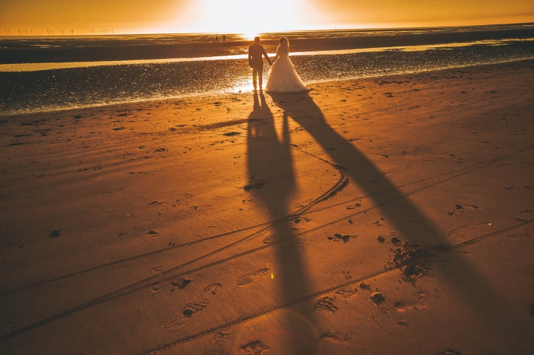 Bride and groom holding hands on beach