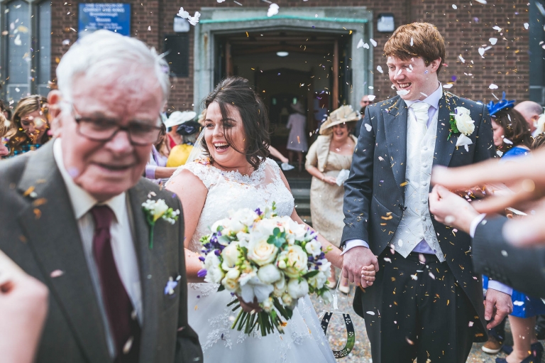 Guest throw confetti over newlyweds