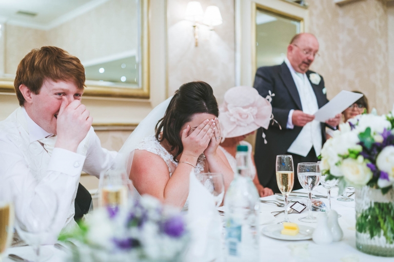 Bride hides face in hands during speeches