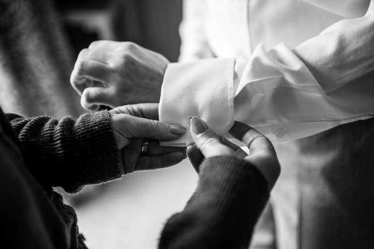 Grooms mother helps the groom with his cufflinks