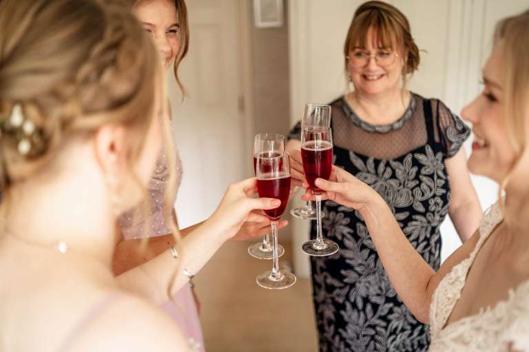 Bride has a glass of champagne with her bridal party