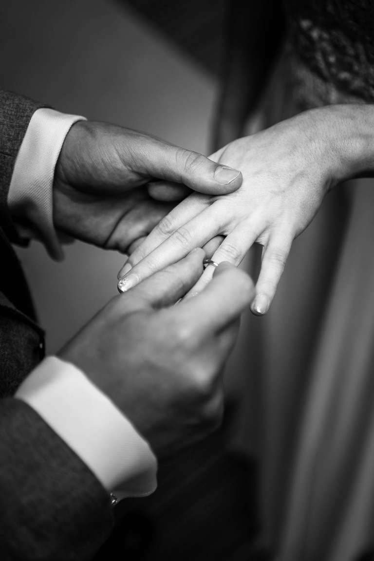 Close up of groom placing ring on brides finger