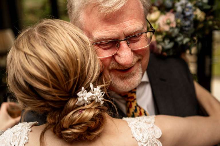 Father of the bride hugs the bride
