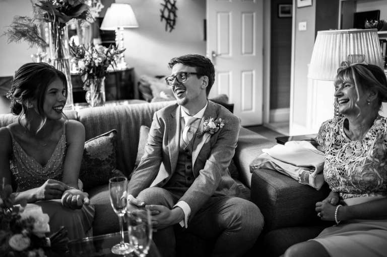 Groom shares a joke with the bridesmaid and mother of the bride
