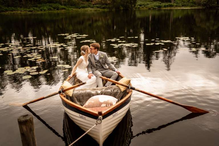 Bride and groom kiss in boat on Gilpin Lake