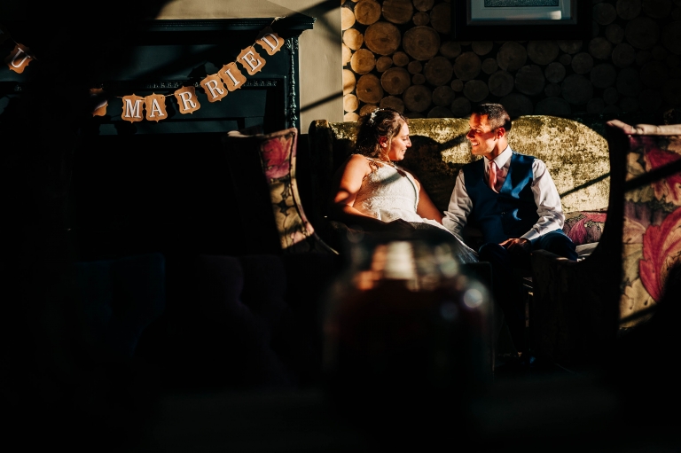 Bride and groom sitting on a chair in the sunlight