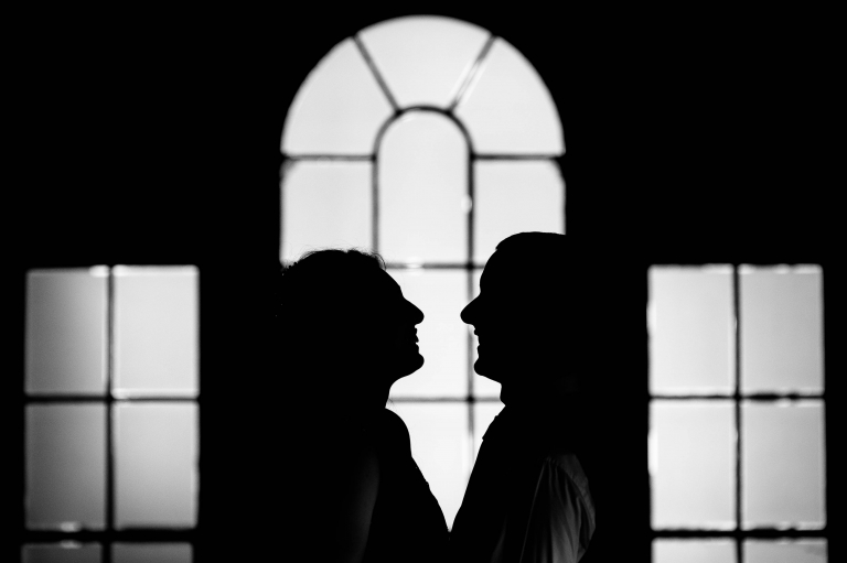 Close up silhouette of bride and groom in window
