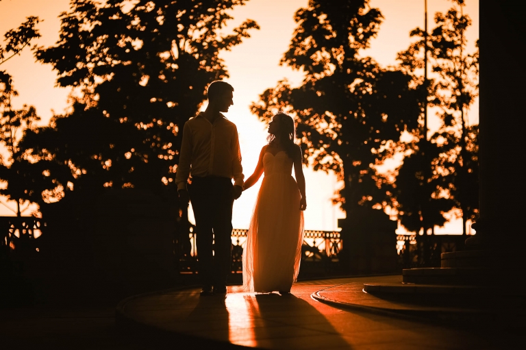 Bride and groom walk together at sunset