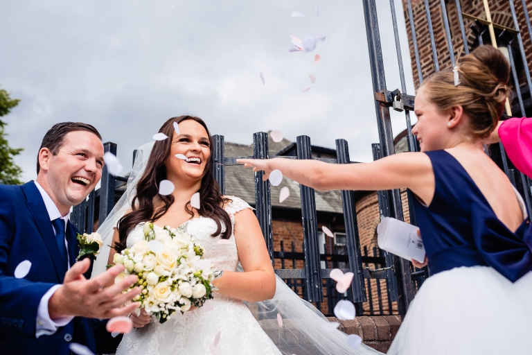Bridesmaid throws confetti over happy couple