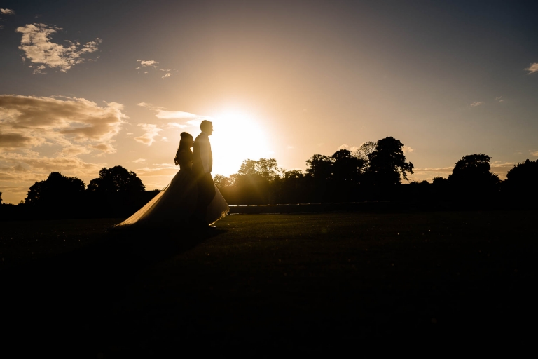 Bride and groom walk together in the sunset