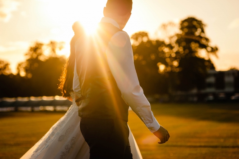 Bride and groom hold hands in the sunset