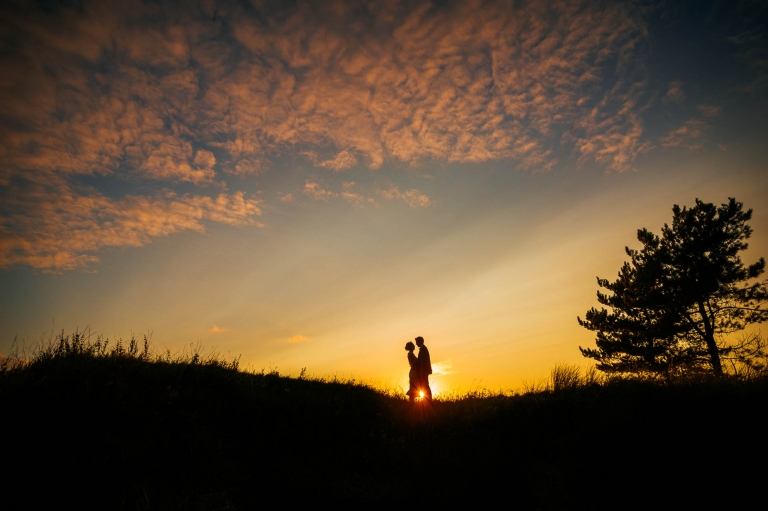 Newlyweds hold each other in the sunset