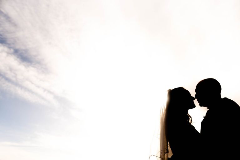 Bride and groom silhouette with sky behind them