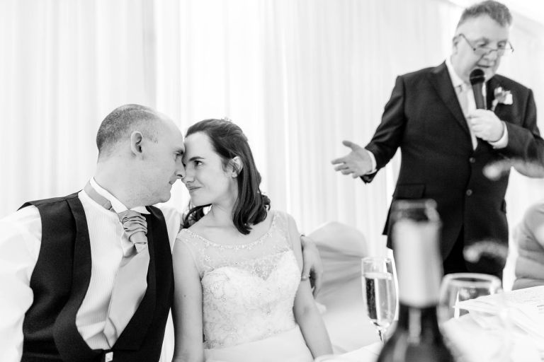 Bride and groom look into each others eyes during father of the grooms speech