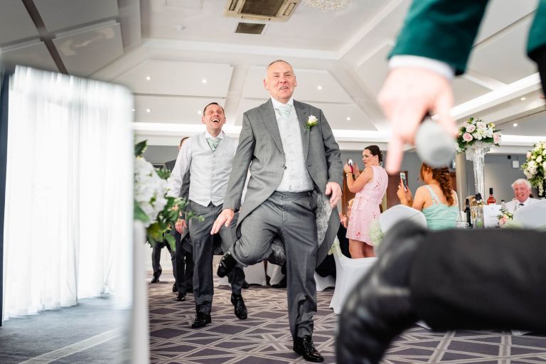 Father of the bride and groomsmen having fun with wedding singer