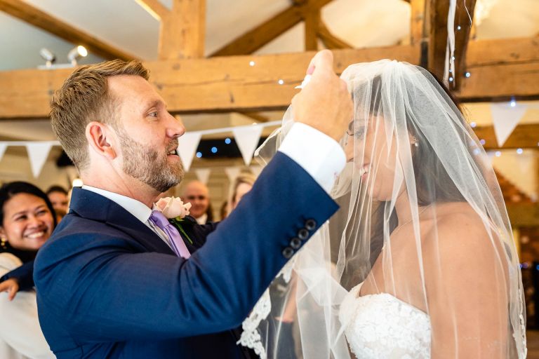 Groom lifts bride's veil