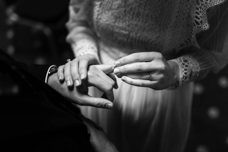 Bride places wedding ring on grooms finger