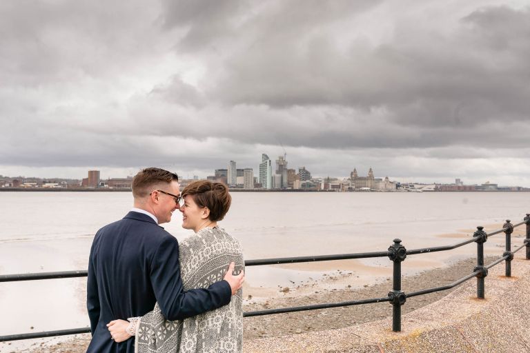 Happy couple look across the Mersey to liverpool skyline