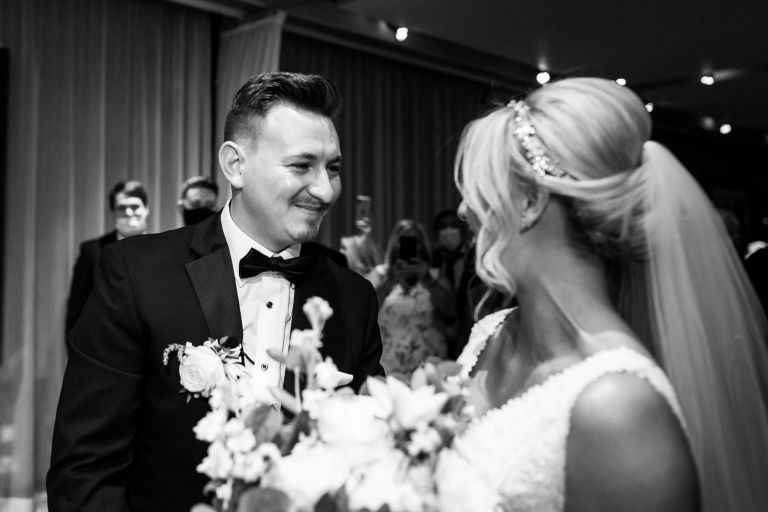 The bride and groom smile at each other as bride gets to end of aisle