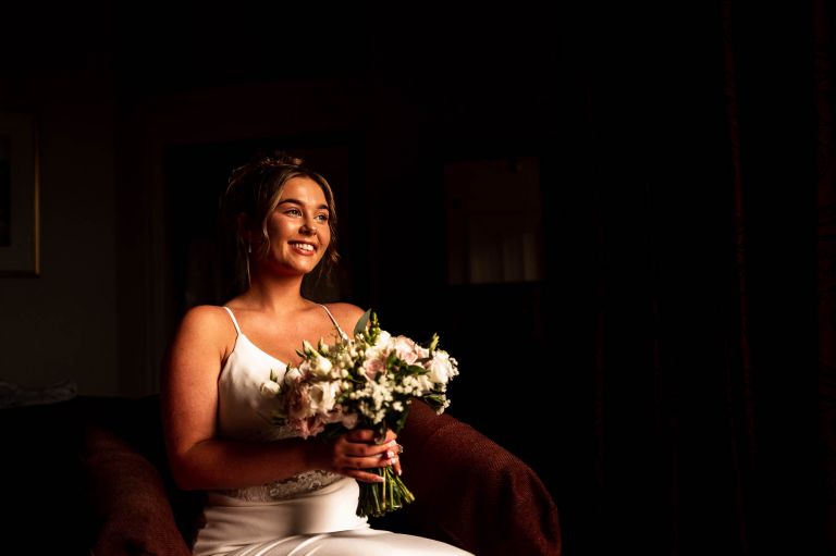 Portrait of bride sitting down with flowers