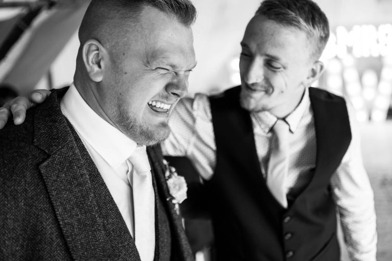 Groom shares a joke with wedding guest