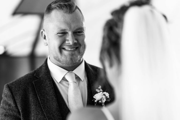Groom smiles at the bride during exchange of rings