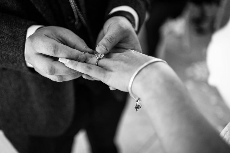 Groom places wedding ring on brides finger