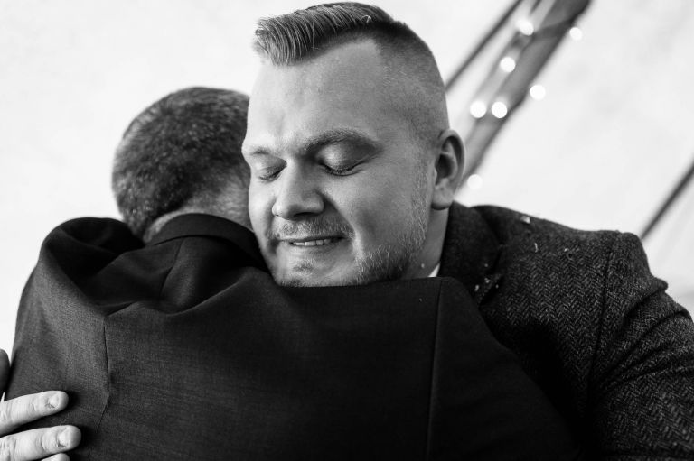 Wedding guest hugs groom