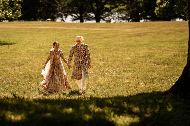 Bride and groom walk in a field