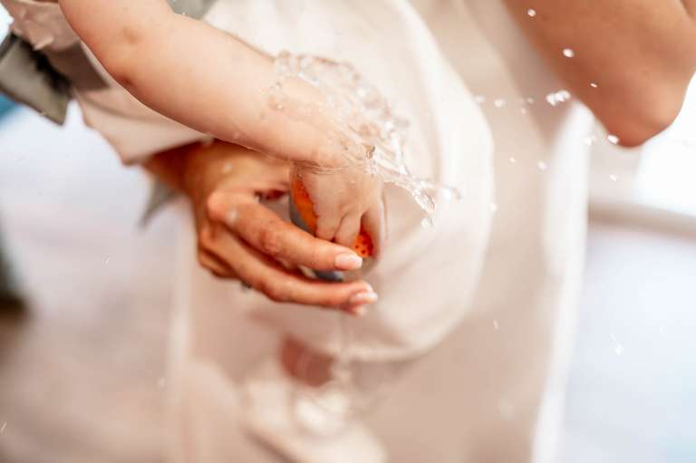 Flower girl puts her tiny hand in brides champagne glass